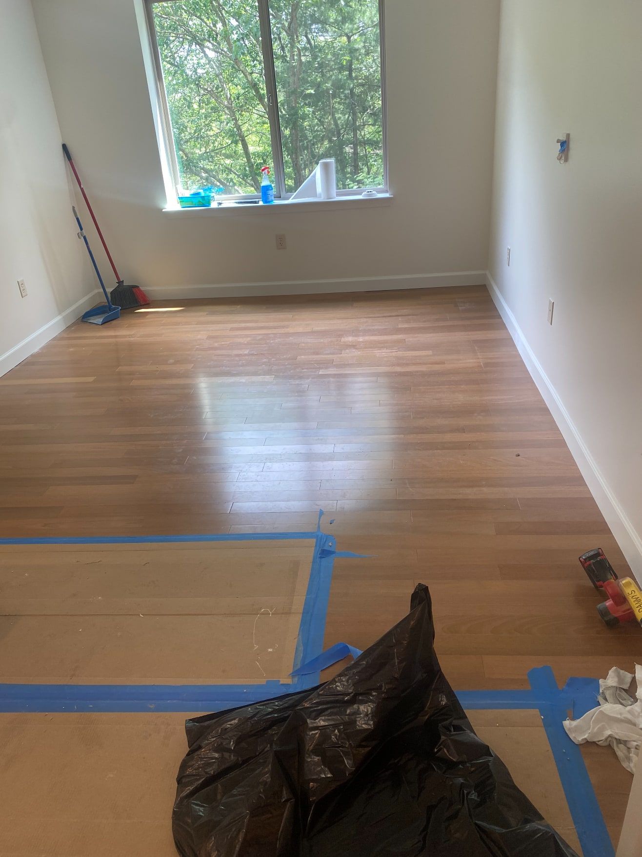 Bright empty bedroom with finished hardwood floor, fresh white walls and new baseboard trim